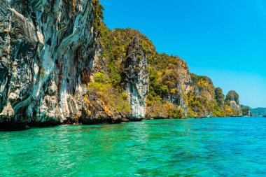 Yeşil ağaçlarla kaplı büyük kaya kayalıkları doğrudan Andaman Denizi 'ne bakıyor. Kayalık ve okyanus manzarası Tayland 'ın Phi-phi Adası' ndaki tropikal turizmin bir simgesidir.
