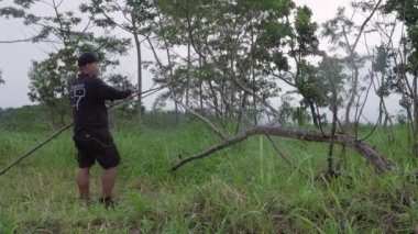Bir adamın tepenin üzerine çarşaf dikme süreci. Ormanın ortasında, Merapi Dağı 'nın göz kamaştırıcı zemininde yalnız bir adam çiselemeden korunmak için bir çarşaf hazırlıyor..