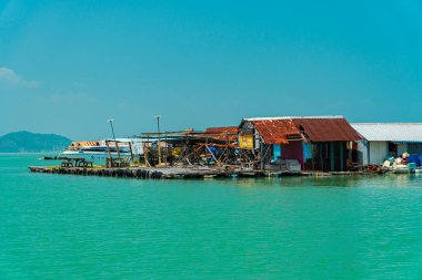 Ufuk çizgisi arasındaki küçük yüzen evler denizi gökyüzünden ayırır ve düzlükler ve dağlar üzerine kurulur. Balıkçılar tarafından balık yetiştirmek için kullanılan yüzen evler.