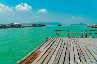 Ufuk çizgisi arasındaki küçük yüzen evler denizi gökyüzünden ayırır ve düzlükler ve dağlar üzerine kurulur. Balıkçılar tarafından balık yetiştirmek için kullanılan yüzen evler.