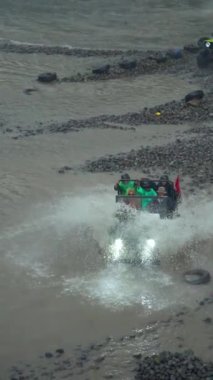 Su her yöne sıçrayıp Merapi Dağı eteğindeki lav turunda yolcuları ıslatana kadar yüksek hızda nehirden geçen bir off-road turist cipinin yavaş çekim görüntüleri.