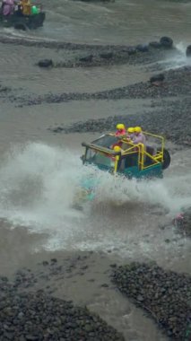 Su her yöne sıçrayıp Merapi Dağı eteğindeki lav turunda yolcuları ıslatana kadar yüksek hızda nehirden geçen bir off-road turist cipinin yavaş çekim görüntüleri.