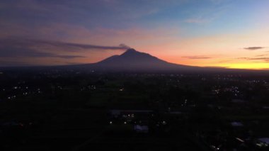 Gökyüzü hala karanlıkken ve güneş doğmadan önce Merapi Dağı 'nın güzelliğinin hava görüntüleri. Merapi Dağı 'nın güzel manzarası. Yükselen güneşten gelen altın renklerle karışık karanlık bir gökyüzü.