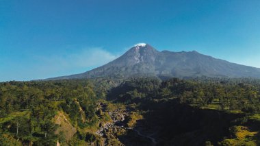 Merapi Dağı 'nın manzarası yazın sabahları çok güzeldir. Aktif volkan manzarası. Önünde orman ve vadi var.