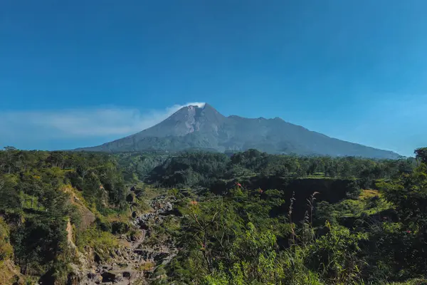 Merapi Dağı 'nın manzarası yazın sabahları çok güzeldir. Aktif volkan manzarası. Önünde orman ve vadi var.