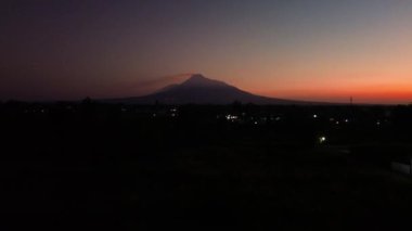 Güneş doğmadan önce gökyüzü hala karanlıkken Merapi Dağı 'nın güzelliğinin 4K hava görüntüsü. Merapi Dağı 'nın panoramik güzelliği. Arkasında kızıl bir gökyüzü var.