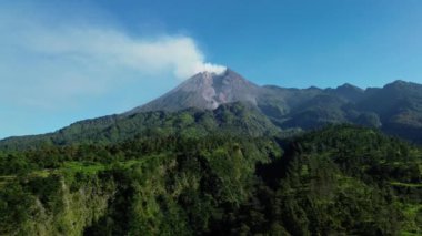 Sabah Merapi Dağı 'nın 4k hava görüntüsü yaz sabahları güzel manzaralı yakın mesafeden. Önünde orman ve yeşil tepeler olan volkanın havadan manzarası.