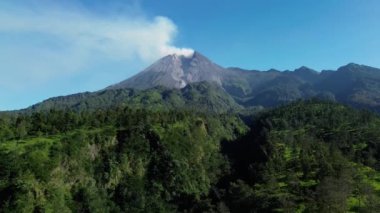 Sabah Merapi Dağı 'nın 4k hava görüntüsü yaz sabahları güzel manzaralı yakın mesafeden. Önünde orman ve yeşil tepeler olan volkanın havadan manzarası.