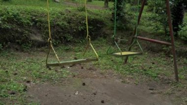 Çam ormanındaki eski ve paslı bir salıncak sandalyesinin 4K video görüntüsü. Yoğun ormanın ortasında, solup paslanana kadar ihmal edilmiş bir sallanan sandalye yavaşça sallanıyordu.