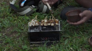 Bushcraft konsepti, yoğun, yeşil bir çam ormanında mangal ızgarasında fıstık soslu tavuk satay pişirir. ASMR ile yemek pişirme ve yeme süreci sakin ve güzel bir doğaya sahip.