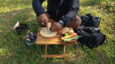 Maceracı ellerinin kömür briketlerini kullanarak bifteği kızartışını yakından çek. Basit ekipman ve malzemelerle doğada yemek ve yemek pişirme kavramı..