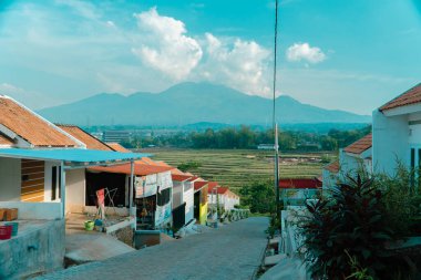 Yeşil pirinç tarlaları ve uzak mesafeden muhteşem görünen dağlarla çevrili güzel manzaralı bir yerleşim yeri. Dağlık manzaralı eğimli tepelerdeki kamu konutları
