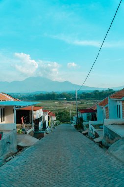 Yeşil pirinç tarlaları ve uzak mesafeden muhteşem görünen dağlarla çevrili güzel manzaralı bir yerleşim yeri. Dağlık manzaralı eğimli tepelerdeki kamu konutları
