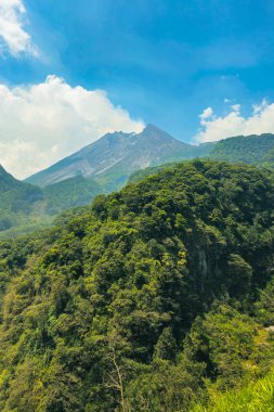Gündüz vakti aktif volkanın yakın çekim manzarası. Yogyakarta, Endonezya 'daki Merapi Dağı ön planda bir tepe ve arka planda bulutlu bir gökyüzü ile yakından bakıldığında gerçekten büyüleyici.