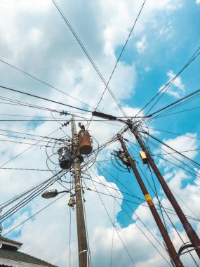 Beton sütunlardaki dağınık elektrik kabloları ve yalıtıcılar. Kentsel bölgelerdeki kabloların ve kabloların düzensiz bağlantısı. Elektrik kabloları ve telefon hatları elektrik direklerinin üzerine kurulmuş.