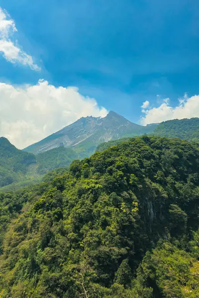 Gündüz vakti aktif volkanın yakın çekim manzarası. Yogyakarta, Endonezya 'daki Merapi Dağı ön planda bir tepe ve arka planda bulutlu bir gökyüzü ile yakından bakıldığında gerçekten büyüleyici.