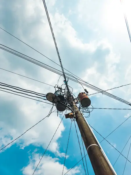 Beton sütunlardaki dağınık elektrik kabloları ve yalıtıcılar. Kentsel bölgelerdeki kabloların ve kabloların düzensiz bağlantısı. Elektrik kabloları ve telefon hatları elektrik direklerinin üzerine kurulmuş.