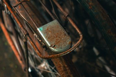 Pas dolu ve yıpranmış klasik bir bisiklete yaklaş. İhmal edilmiş ve tozla dolu eski bisiklet parçaları paslanmaya ve gözeneklenmeye başlamış gibi görünüyor.