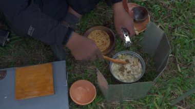 Roti Canai ile köri pişirirken çam ormanlarında tek başına kamp yapma fikri. Asyalı bir erkek maceracı, güzel doğada yemek pişirip hazırlanırken tek başına kamp yapar.