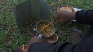 Roti Canai ile köri pişirirken çam ormanlarında tek başına kamp yapma fikri. Asyalı bir erkek maceracı, güzel doğada yemek pişirip hazırlanırken tek başına kamp yapar.