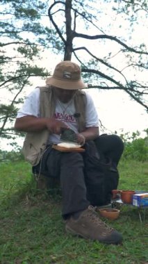 Bushcraft kavramı, yoğun ve yeşil bir çam ormanında soya soslu kızarmış tempeh pişirir. Asyalı bir erkek yalnız maceracı güzel bir doğada hazırlık ve yemek yapma sürecinde.
