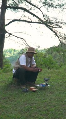 Bushcraft kavramı, yoğun ve yeşil bir çam ormanında soya soslu kızarmış tempeh pişirir. Asyalı bir erkek yalnız maceracı güzel bir doğada hazırlık ve yemek yapma sürecinde.