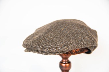 Detail of a scally cap or flat hat or herringbone wool fabric hat mounted on a bronze mannequin head with a white background. Concept photo of a classic dark khaki hat on an elegant bronze mannequin clipart