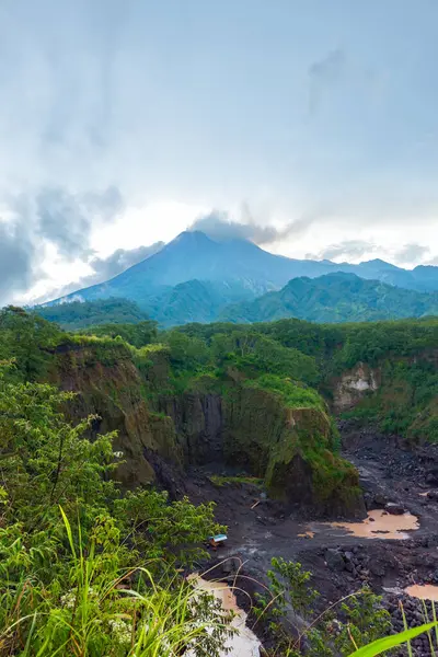 Merapi Dağı 'nın panorama' sı, öğleden sonra bulutların etrafını sardığı yakın bir mesafeden. Önünde kayalar ve vadi olan güneyden aktif volkan manzarası.