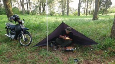 Çam ormanı bölgesinde kamp ve macera aktiviteleri bir tuzak kurarak ve yumurtalı pilav ve odun sobası kullanarak sıcak çay pişirerek. Bushcraft kavramı, doğada basit ekipman ve malzemelerle yemek pişirmek ve yemek yapmaktır..