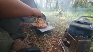 Çam ormanı bölgesinde kamp ve macera aktiviteleri bir tuzak kurarak ve yumurtalı pilav ve odun sobası kullanarak sıcak çay pişirerek. Bushcraft kavramı, doğada basit ekipman ve malzemelerle yemek pişirmek ve yemek yapmaktır..