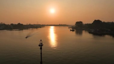 Gün batımında hava manzarası ve körfezde güzel bir manzarası olan turuncu gökyüzü. Altın sarısı alacakaranlıkta körfezi geçen bir geminin 4k hava görüntüsü.