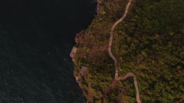 Güneş battığında doğrudan denize dokunan tepenin güzelliği. Kumsalın kenarındaki tepe bölgesinin temiz bir görüntüsü var.