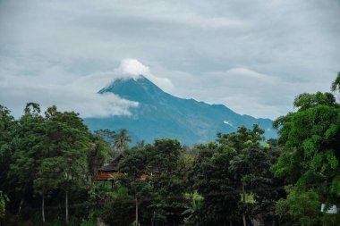Merapi Dağı 'nın öğleden sonra etrafında sıra sıra bulutlar olan yakın görüntüsü. Güney tarafındaki aktif volkanın ön tarafında kayalar ve vadiler olan yakın plan fotoğrafı.