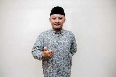 Bronz tenli, desenli gömlek giyen, siyah şapkalı, beyaz arka planda çeşitli el işaretleri yapan Asyalı bir adamın izole edilmiş konsept fotoğrafı. Cava 'lı adam beyaz arka planda çeşitli pozlar veriyor.