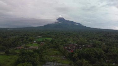 Akşamüstü, önünde yemyeşil ağaçlardan oluşan bir panorama olan aktif bir volkanın havadan görüntüsü. Drone görüntüleri Sleman, Yogyakarta, Endonezya 'daki Merapi Dağı' nın güzelliğini gösteriyor.