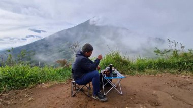 Tepenin üstünde güzel bir dağ zeminli V60 kahve yapma süreci. Bushcraft konsepti, parlak bir sabahta bir dağ zeminli platoda V60 kahve yapmaktır.