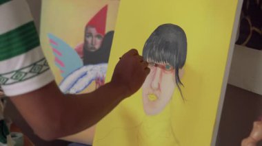 Fırça kullanarak tuvale parlak renkler uygulayan bir sanatçı. Bir ressamın bir kızın yüzünü pop tarzında boyama işleminden fırça darbelerine yakın çekim