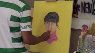 Fırça kullanarak tuvale parlak renkler uygulayan bir sanatçı. Bir ressamın bir kızın yüzünü pop tarzında boyama işleminden fırça darbelerine yakın çekim