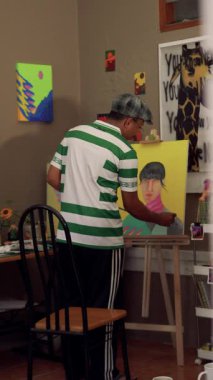 Bir ressamın, fırça kullanarak tuvale parlak renkler uyguladığı bir video görüntüsü. Bir ressamın bir kızın yüzünü pop tarzında boyama işleminden fırça darbelerine yakın çekim