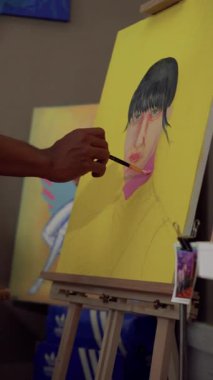 Bir ressamın, fırça kullanarak tuvale parlak renkler uyguladığı bir video görüntüsü. Bir ressamın bir kızın yüzünü pop tarzında boyama işleminden fırça darbelerine yakın çekim