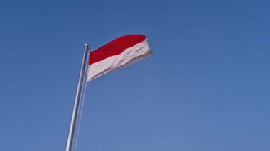Endonezya ulusal bayrağının sabah açık mavi gökyüzüne karşı bir dağın tepesinde dalgalandığı görüntüler. Endonezya Bağımsızlık Günü 'nde mavi gökyüzüne doğru dalgalanan Endonezya bayrağının yakın çekimi.