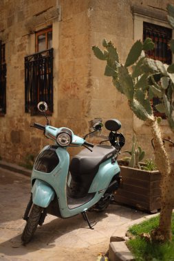 Eski kasabanın duvarının yakınına park edilmiş mavi scooter..