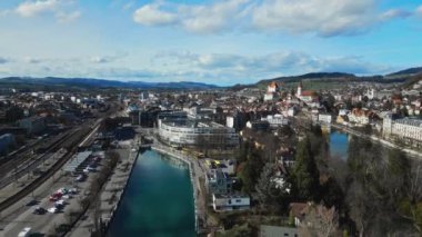 İHA görüntüleri, hava görüntüsü. İnsansız hava aracından bir şehri filme almak. Şehrin üzerinde uçuyor. Avrupa şehir manzarası. Otobüs durağı. Park alanı. Otobüs terminali. Sarı otobüs. Tarihi eski kasaba. Nehir şehrin içinden akıyor.