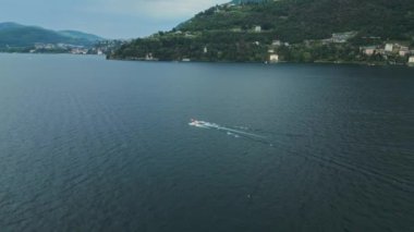 Tekne göle gidiyor. Sürat teknesi suda yüzüyor. Yat nehirde hızlı gidiyor. Dağlardaki göl. Lugano. İtalya. Como Gölü. Dağlık arazi. Dağ manzarası. Hava görünümü