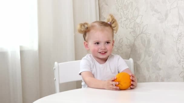 Маленька Дівчинка Білій Футболці Сидить Столом Грає Великим Апельсином — стокове відео