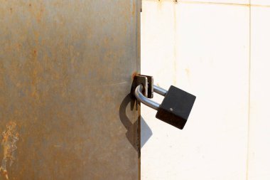 Kapıda eski bir asma kilit asılı.