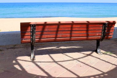 Akdeniz kıyısındaki bir şehir parkında dinlenmek için bankta..