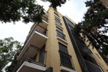 Tel Aviv İsrail 03 / 28 / 2024. Tel Aviv 'deki binalar ve yapılar yüksek ağaçların yaprakları arasında..