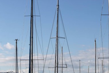 Mavi gökyüzüne karşı limanda direkler.