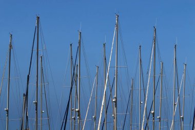 Mavi gökyüzüne karşı limanda direkler.